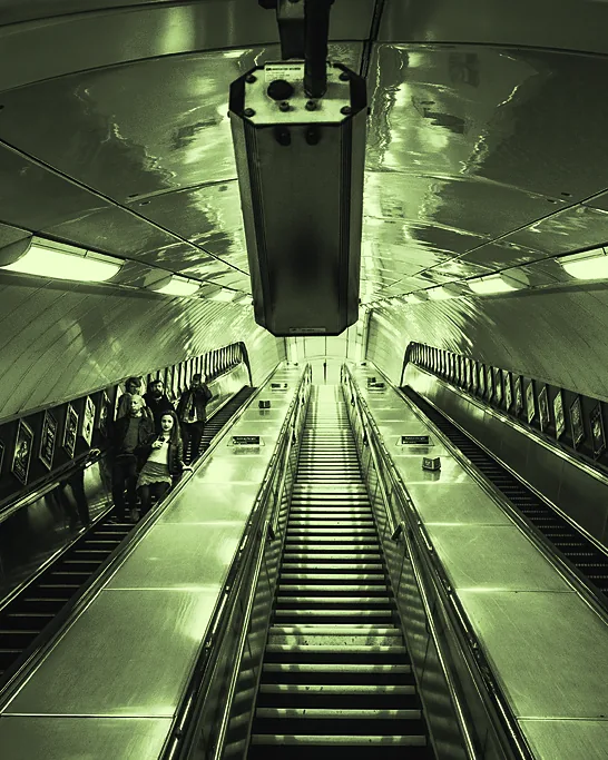 A long escalator descending under a curved, lit tunnel roof