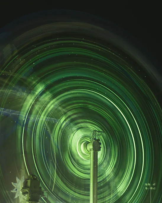 Rings of green light spiralling around a pole in a long exposure