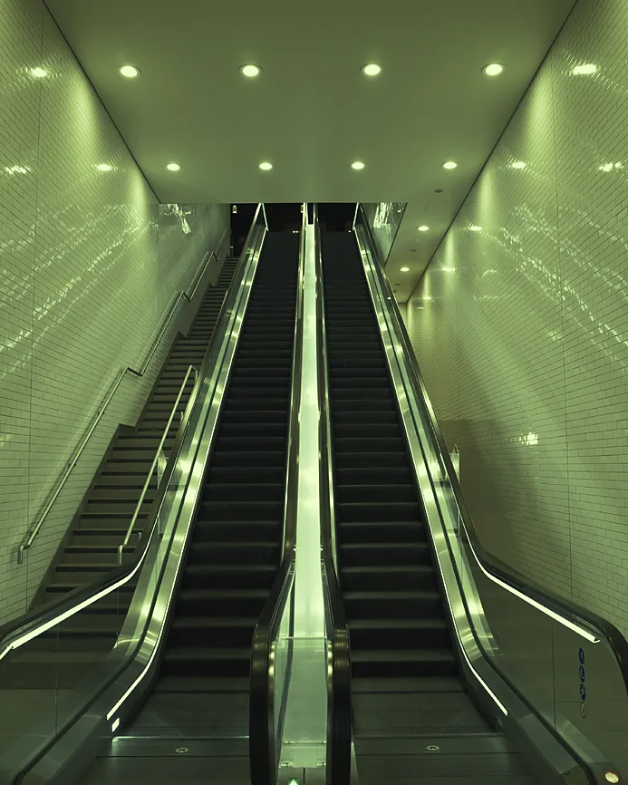 Twin escalators rising between bright, bare walls